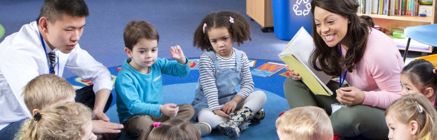 Group of kids sitting in a circle with teachers
