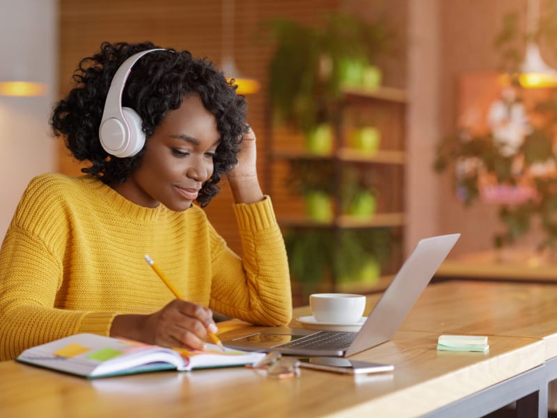 Person studying at a table with her laptop and notebook
